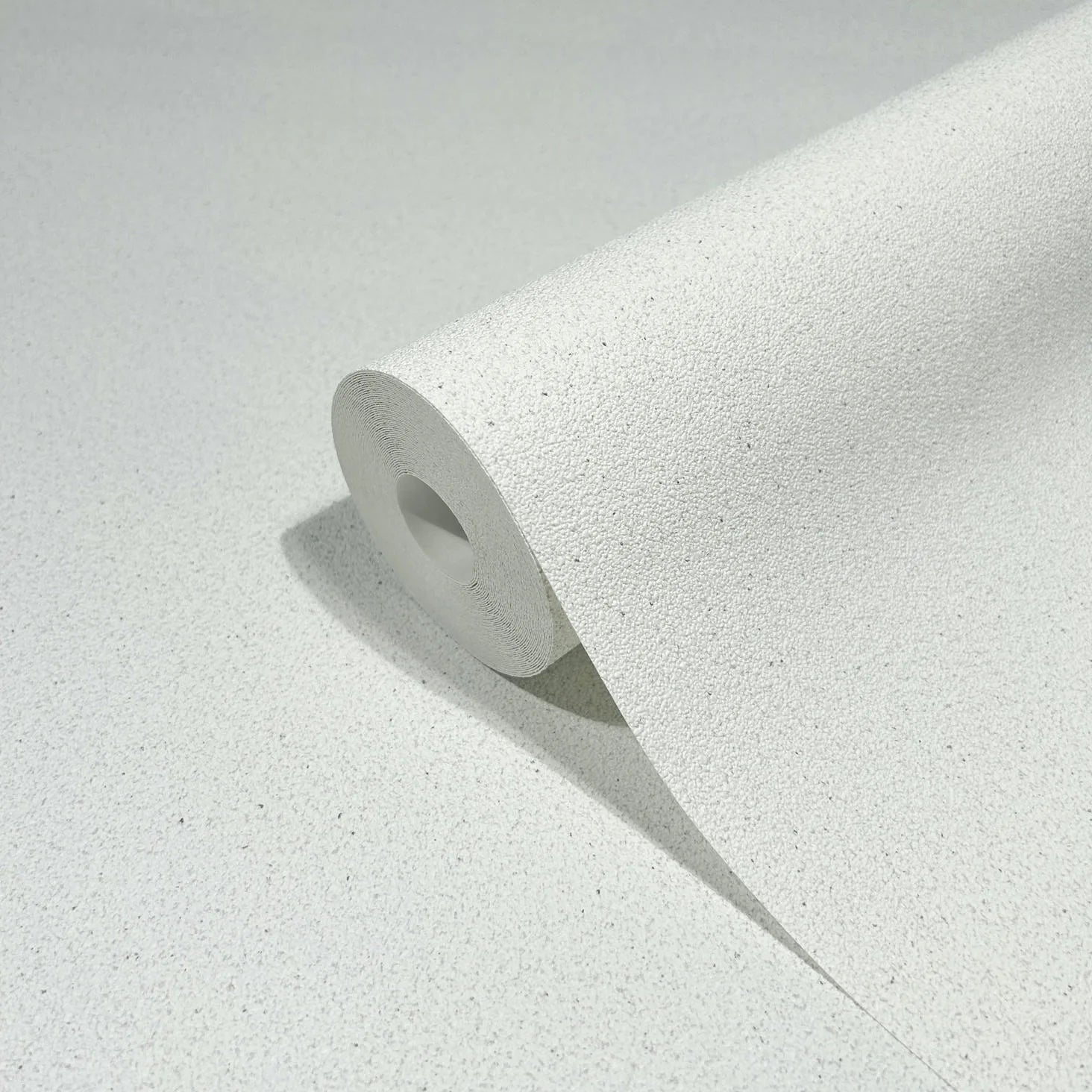 Marburg Travertino 33364 Close-up of a white speckled textured wallpaper roll on a matching unrolled sheet.