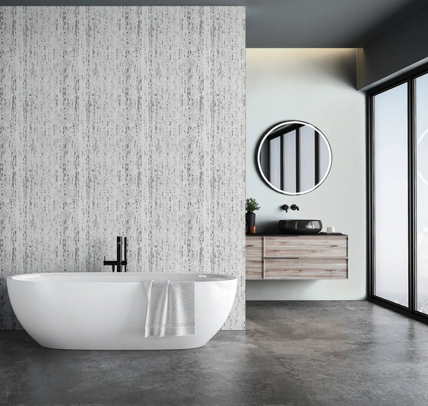 Marburg Travertino 33364 Bathroom scene with a white wallpapered feature wall of vertical gray streaks behind a freestanding tub, alongside a floating vanity with a round mirror and large windows.