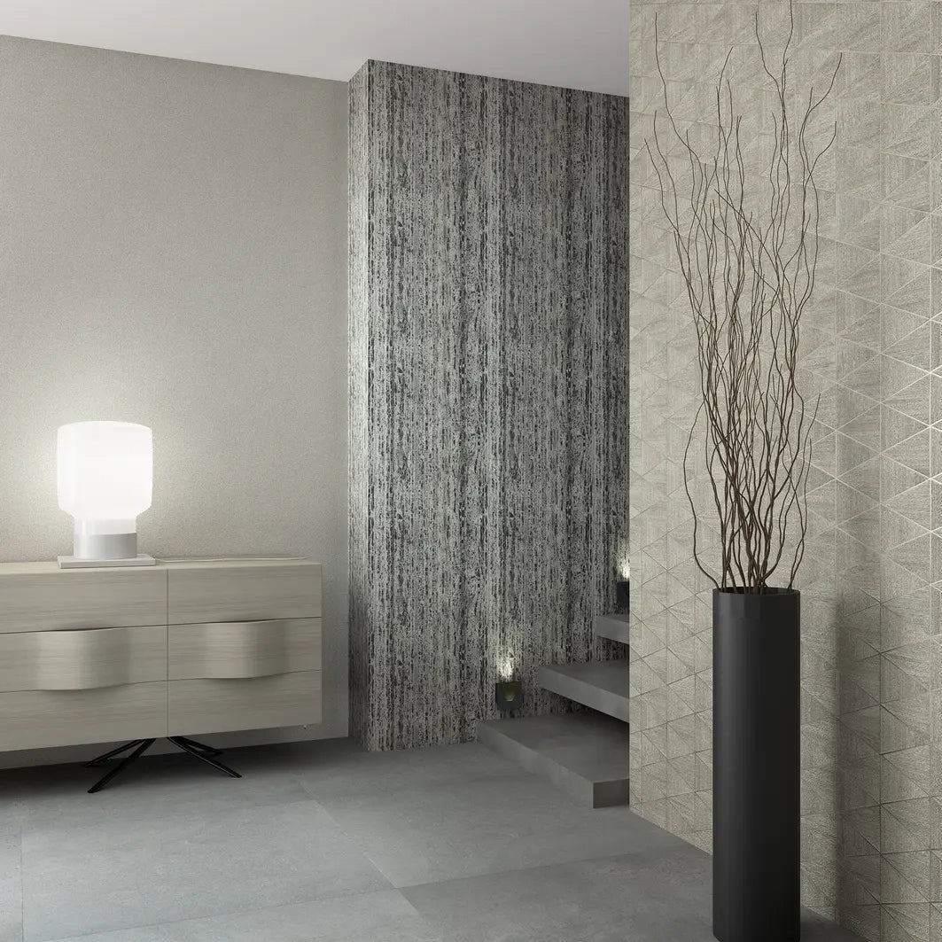 Marburg Travertino 33366 Modern stair area with a right wall in gray geometric triangle wallpaper, a center wall in dark vertically striated wallpaper, and a plain light gray wall. A low sideboard with a glowing table lamp sits on the left, open steps with small step lights lead up, и.