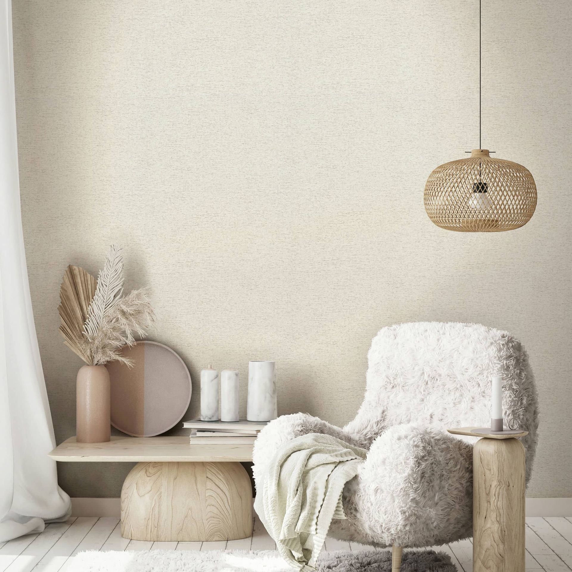 Marburg Travertino 33367 Beige textured wallpaper shown in a styled living room corner with a wicker pendant light, a fluffy white armchair, a small wooden side table with a candle, and a low wood bench holding a vase with dried leaves and grasses, a round tray, and candles; a sheer a.