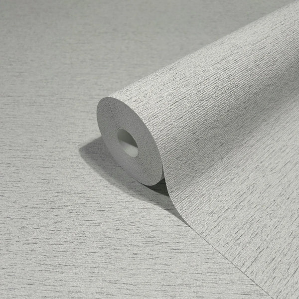 Marburg Travertino 33369 Close-up of a gray textured wallpaper roll resting on a matching unrolled sheet, showing a fine horizontal striated texture.