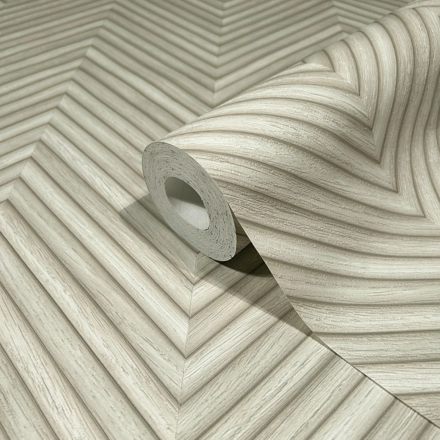 Marburg Travertino 33373 A wallpaper roll resting on matching beige chevron-patterned paper with fine striated lines forming V-shaped bands.