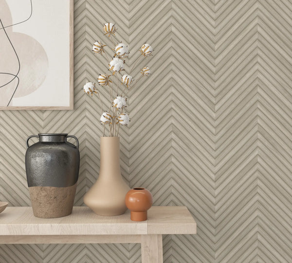 Marburg Travertino 33373 Beige chevron (herringbone) wallpaper with narrow ribbed bands creating V-shaped stripes and a stone wallpaper on a styled interior feature wall.