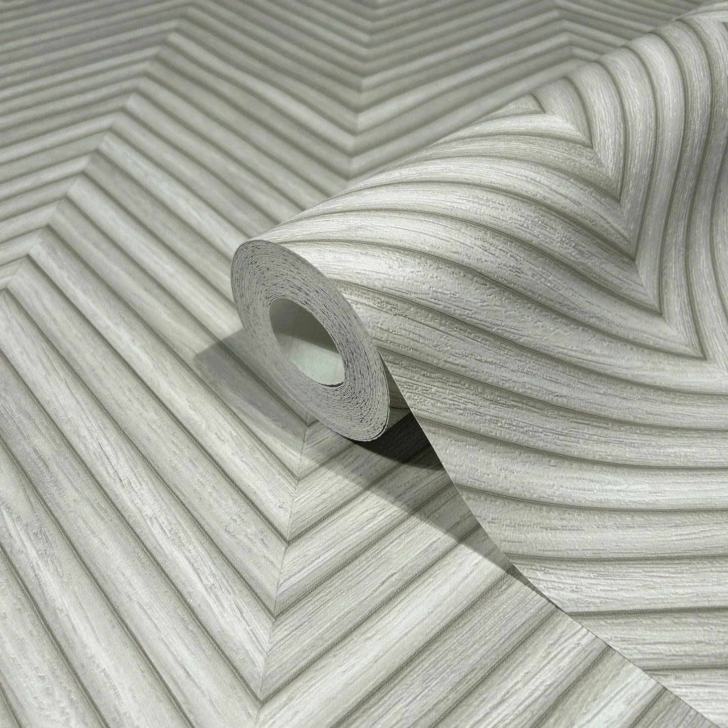 Marburg Travertino 33374 A wallpaper roll resting on an unrolled sheet showing a gray chevron-style pattern of diagonal ridged lines.