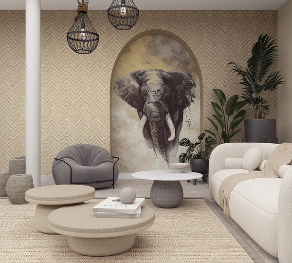 Marburg Travertino 33376 Living room scene with beige herringbone wallpaper and an arched niche featuring an elephant mural, styled with a light sofa, round coffee tables, a gray armchair, pendant lights, a rug, and potted plants.