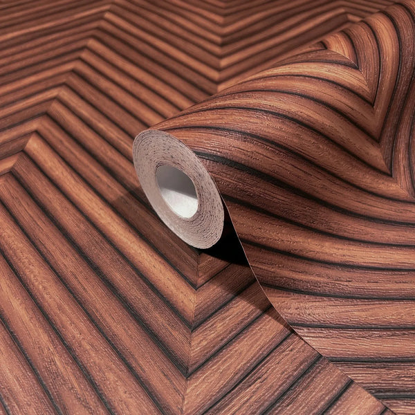 Marburg Travertino 33379 A wallpaper roll resting on an unrolled sheet showing a brown woodgrain chevron pattern with dark stripes.