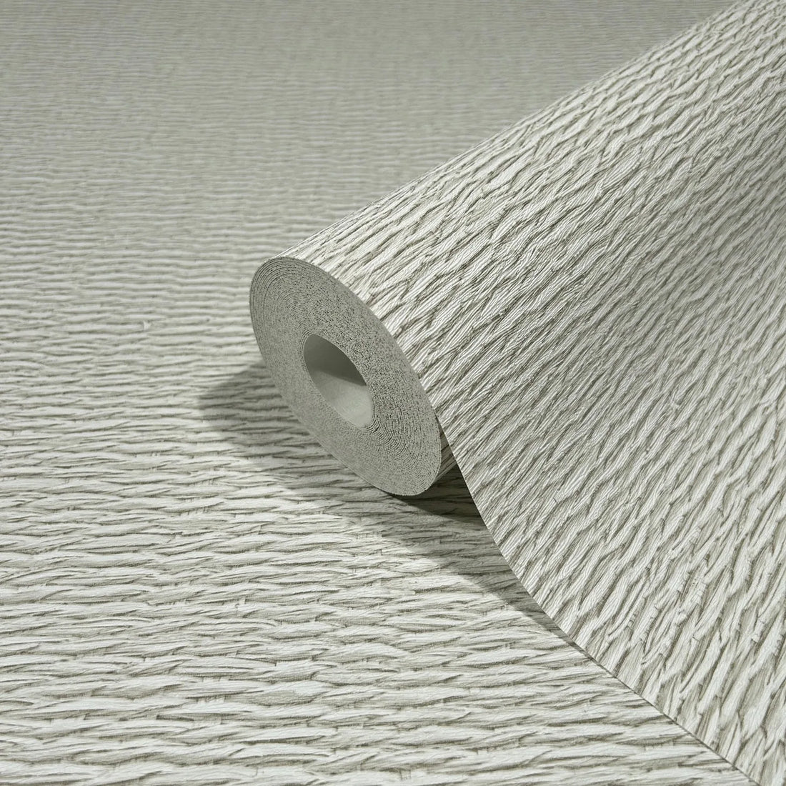 Marburg Travertino 33382 Close-up of light beige wallpaper with irregular horizontal ripple lines, styled with a sculptural ring-shaped vase holding dried stems.