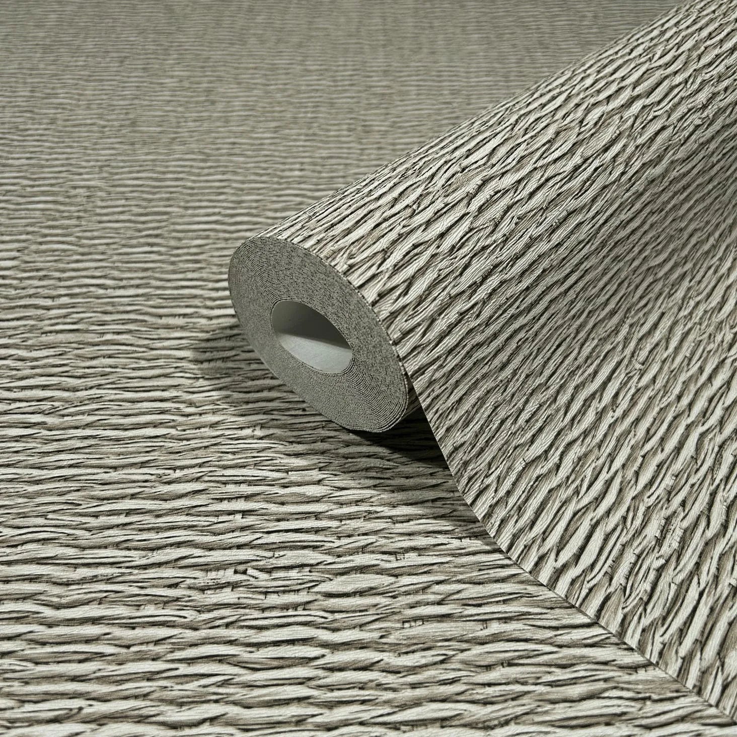 Marburg Travertino 33383 Close-up of a beige and brown textured wallpaper roll with irregular horizontal ridges, partially unrolled on the same pattern.