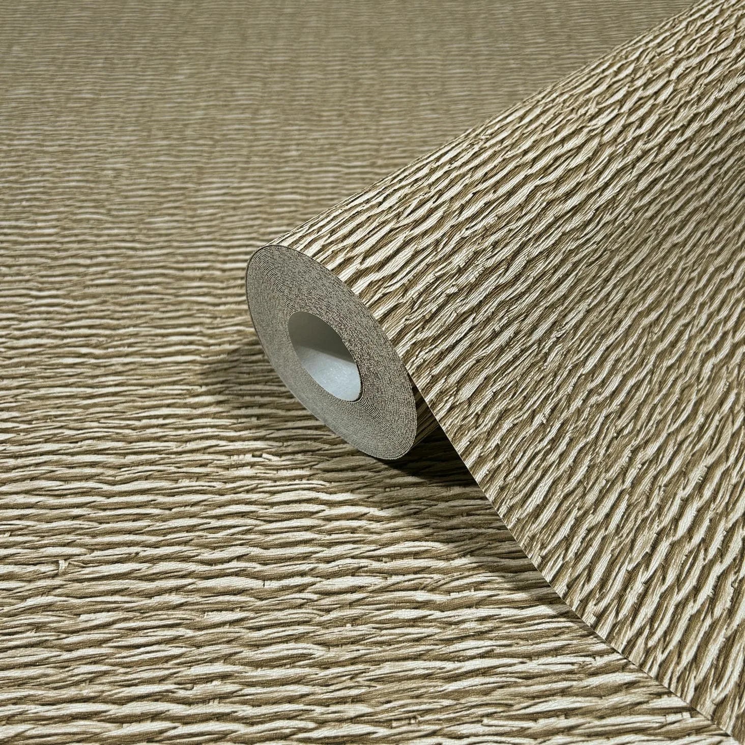 Marburg Travertino 33384 Close-up of a beige wallpaper roll with horizontal ridged texture, resting on the same unrolled wallpaper.