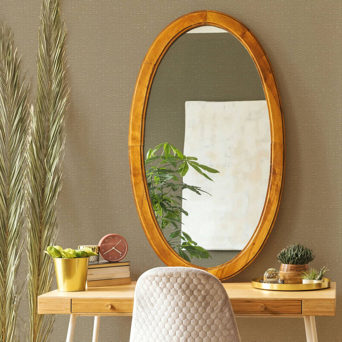 Marburg Travertino 33384 Textured beige wallpaper with subtle horizontal lines behind a wooden desk scene featuring an oval wood-framed mirror, upholstered chair, potted plants, a small clock, books, and a tray.