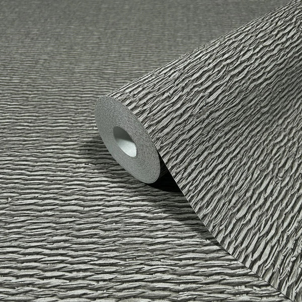 Marburg Travertino 33386 Close-up of a gray wallpaper roll with raised horizontal ridges, resting on the same textured pattern.