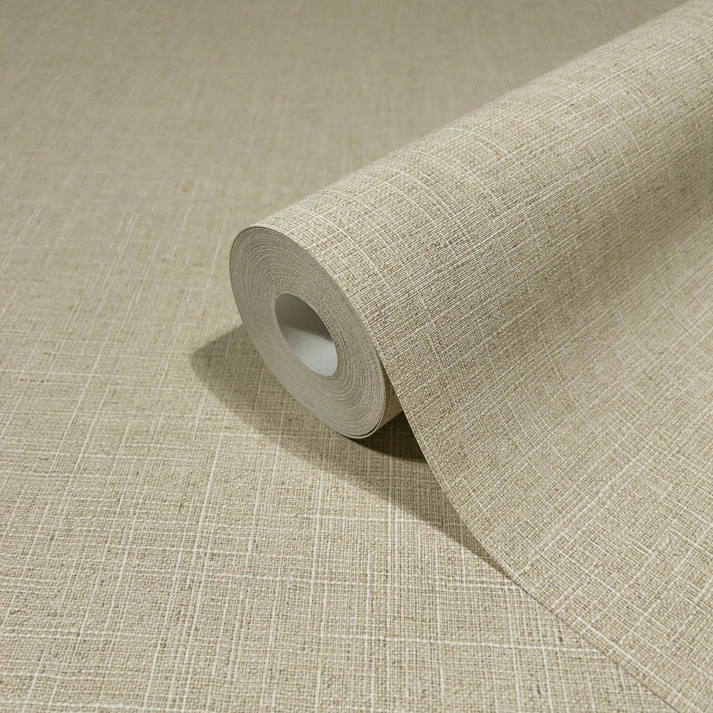 Marburg Travertino 33392 A beige wallpaper roll with a fine crosshatch texture, partially unrolled on a matching surface.