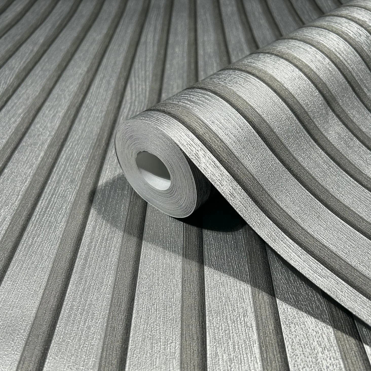 Marburg Travertino 33395 Close-up of a silver textured wallpaper roll with raised linear stripes resting on the same matching pattern.