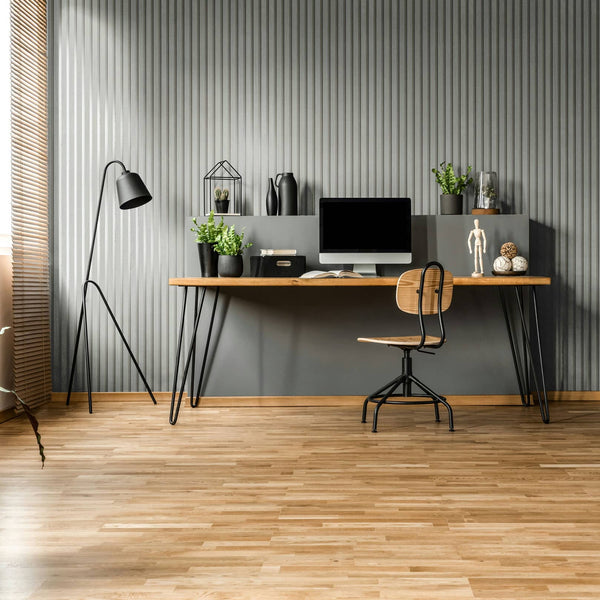 Marburg Travertino 33395 Gray vertical ribbed wallpaper forms the backdrop for a modern home office with a wood desk, chair, computer monitor, black floor lamp, and potted plants.