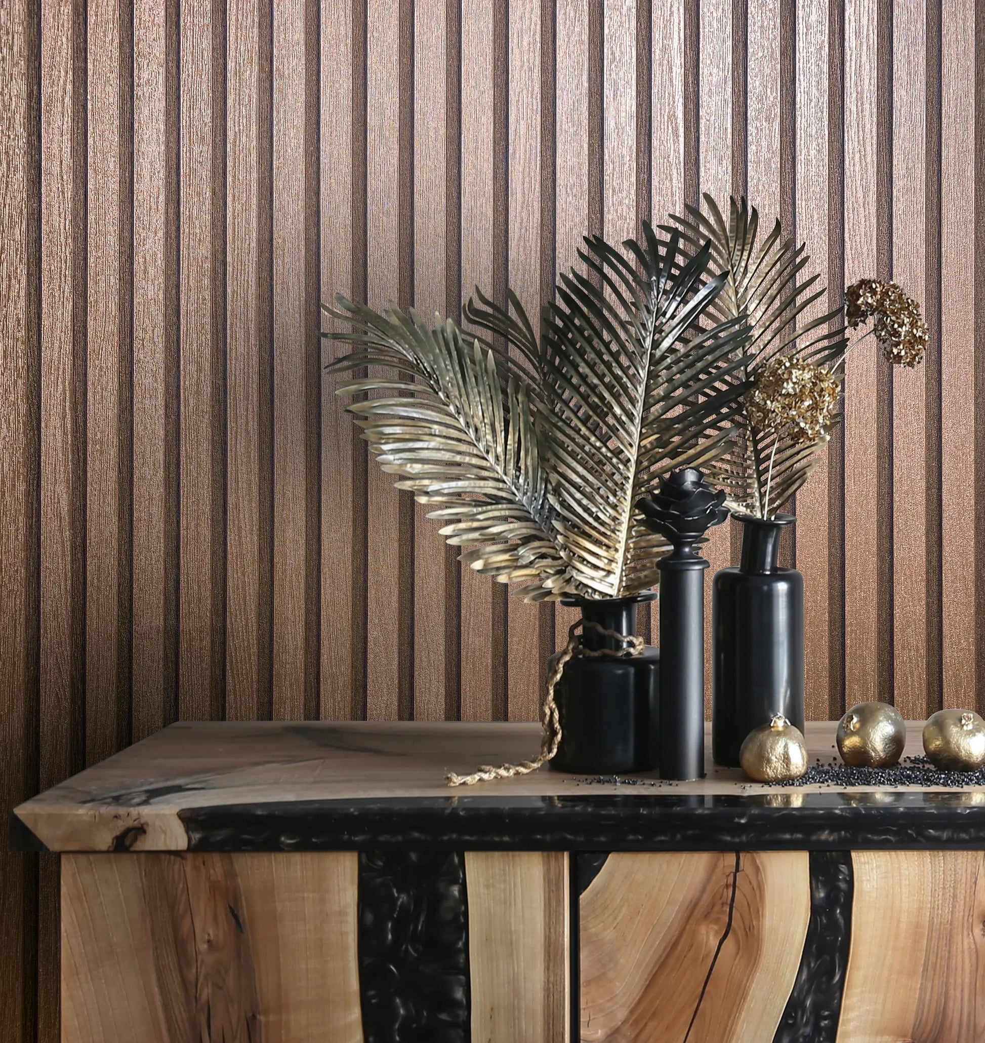 Marburg Travertino 33397 Vertical ribbed textured wallpaper in metallic copper behind a wood console styled with black vases, metal leaf stems, and small gold ornaments.