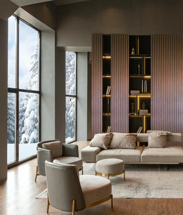 Marburg Travertino 33397 Contemporary living room featuring a feature wall clad in warm copper-toned vertical striped wallpaper around illuminated built-in shelves. A neutral sofa with cushions, two armchairs, ottomans, a rug, wood flooring, and tall windows with snowy trees outside.